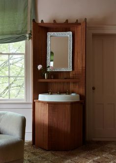 a bathroom with a chair, mirror and sink in it's corner next to a window