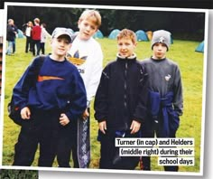 a group of young boys standing next to each other on top of a grass covered field