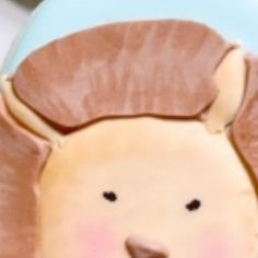 a close up of a cake with a lion on it's face and ears