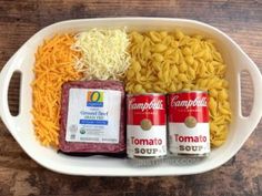 two cans of soup, noodles and cheese in a white dish on a wooden table