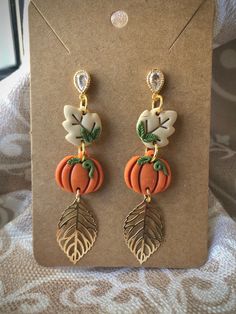 a pair of earrings with leaves and pumpkins on them