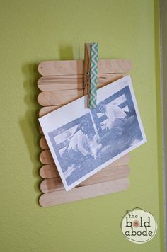 an old photo hangs on a clothes peg and is attached to a green wall with a clip