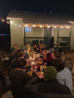 a group of people sitting around a table with food and drinks on it at night