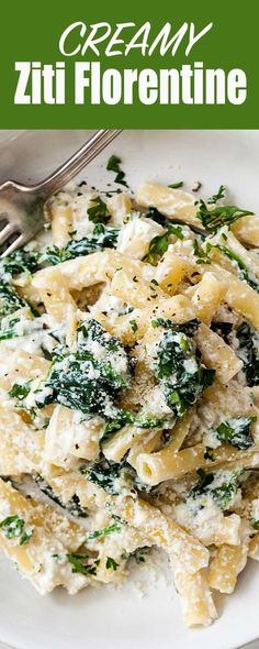 a white plate topped with pasta covered in cheese and spinach next to a fork