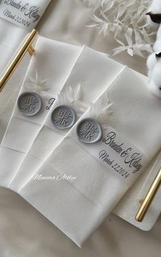 three white napkins with monogrammed initials on them and gold pen laying next to each other