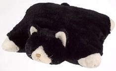 a black and white stuffed animal laying on top of a white surface with its eyes closed