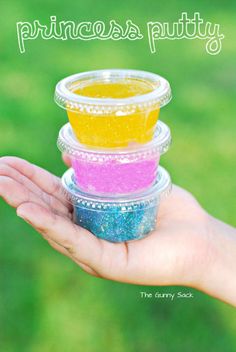 someone is holding three small containers with different colored food in them and there are grass in the background