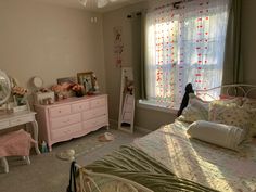 a bedroom with a bed, dresser and window in the corner that has flowers on it