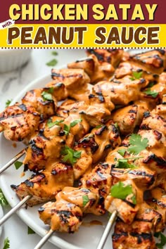 chicken satay with peanut sauce on a white plate and garnished with cilantro