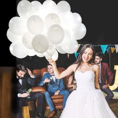 a woman in a wedding dress is holding balloons and posing for the camera with her friends