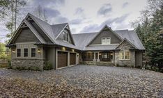 a large house in the woods with lots of leaves on the ground