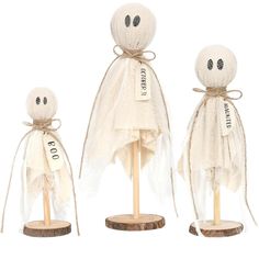 three wooden dolls are dressed in white cloths