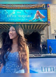 a beautiful young lady standing in front of a sign for the little mermaid musical theatre