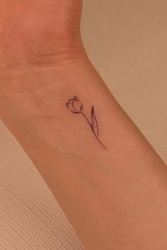 a small wrist tattoo with a single tulip on the left side of the arm