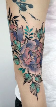 a woman's arm with flowers and leaves tattooed on the side of her body