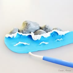 a toothbrush sitting on top of a blue plate with rocks and water in it