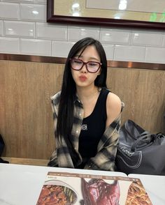 a woman sitting at a table with a book in front of her on the table