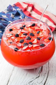 a drink in a glass with strawberries and blackberries on the rim next to an american flag