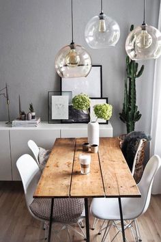 a dining room table with white chairs and hanging lights