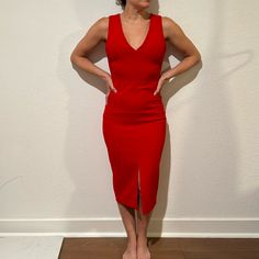 a woman in a red dress standing on a wooden floor with her hands on her hips