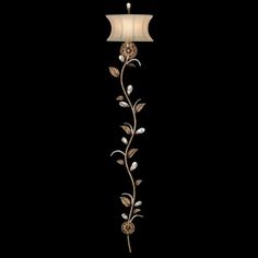 a floor lamp with flowers and leaves hanging from it's side on a black background