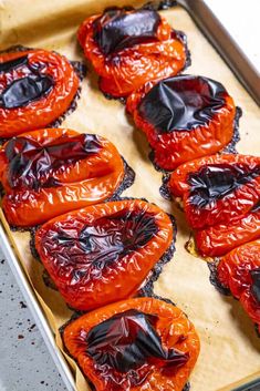 several pieces of cooked red peppers on a baking sheet lined with plastic wrapper, ready to be baked