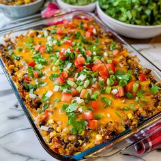 a casserole dish filled with mexican food and garnished with cilantro