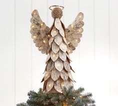 an angel statue on top of a christmas tree decorated with lights and tinsels