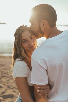 a man and woman standing next to each other at the beach with sun shining on them