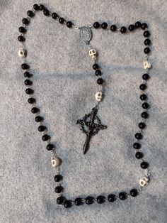 A hand crafted rosary inspired by the "Momento Mori" teachings.  Made with black-coated glass beads and beige resin skull shaped beads. The crucifix is a nail and crown of thorns style, metal, and Italian made with gunmetal finish.  The centerpiece is Italian made, metal, and gunmetal finish. The beads are connected with hand twisted wire and metal rings. Gothic Moodboard, Skull Rosary, Punk Fashion Diy, Resin Skull, Momento Mori