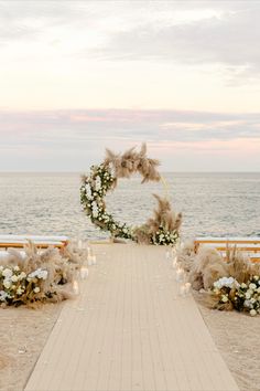 an outdoor ceremony setup with pamolite and white flowers on the aisle leading to the ocean