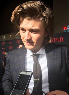 a man in a suit and tie holding an electronic device while standing next to him