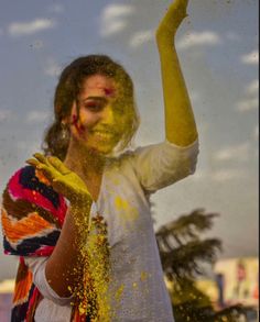 a man covered in yellow powder and throwing it up into the air with his hand