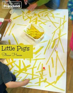 two children are sitting at a table with yellow paint on it and one child is painting the paper