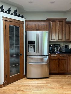 a metallic refrigerator freezer sitting inside of a kitchen next to wooden cabinets and drawers