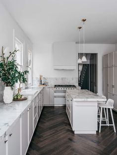 a kitchen with white cabinets and marble counter tops, along with an island in the middle