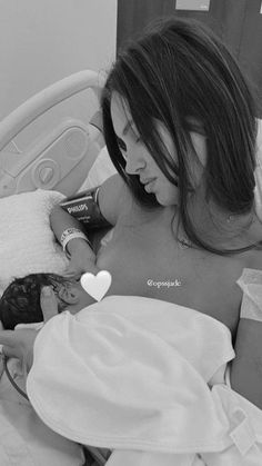 a woman laying in bed next to a small child with a heart on her chest