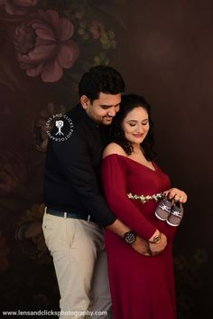 a pregnant woman in a red dress standing next to a man wearing a black shirt