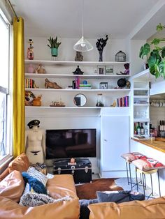 a living room filled with furniture and a flat screen tv sitting on top of a wooden shelf