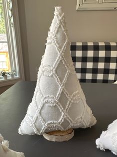 a small white christmas tree sitting on top of a table next to a pillow and blanket