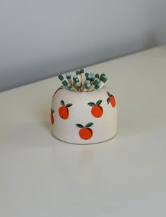 an orange and white ceramic pot with toothbrushes in it on top of a table