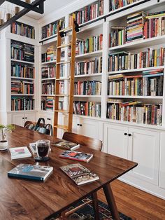 a long table with books on it in front of a book shelf filled with books