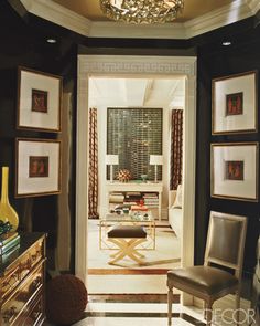 a living room with black walls and pictures on the wall, chairs and a chandelier