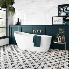 a white bath tub sitting next to a window in a room with black and white tiles