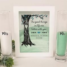 two glass vases sitting next to each other near a picture frame with the words, the good things in life are better with you