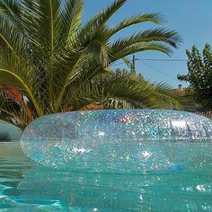 an inflatable ball floating on top of a pool next to a palm tree