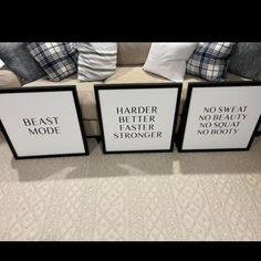 three black and white framed signs sitting on top of a couch