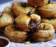 there are many small pies with toppings on the table next to some dipping sauce