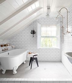 an attic bathroom with white brick walls and flooring, along with a claw foot tub