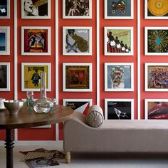 a living room with red walls and pictures on the wall behind the couch is a coffee table